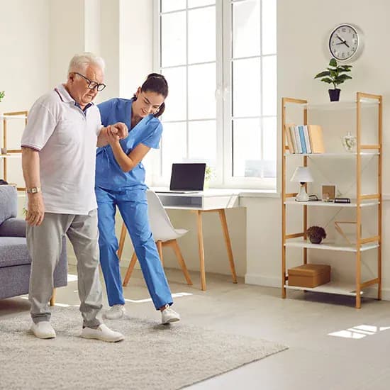 Care worker supporting an older resident walking in a bright care home room