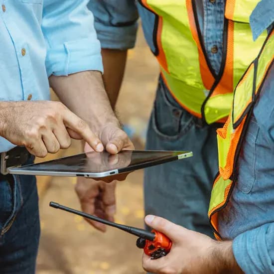Groundworks team checking site information on a tablet while holding a walkie-talkie