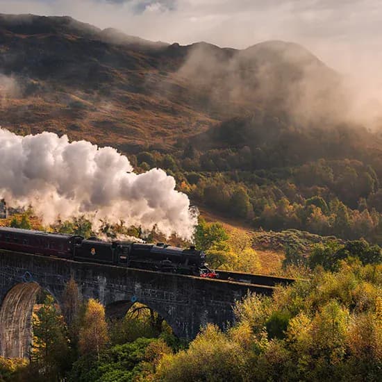 Heritage steam train crossing a viaduct through mountain scenery
