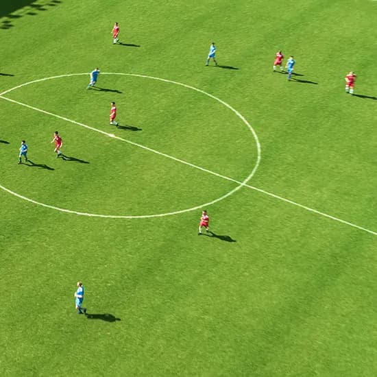 Football match taking place on a bright green pitch viewed from above