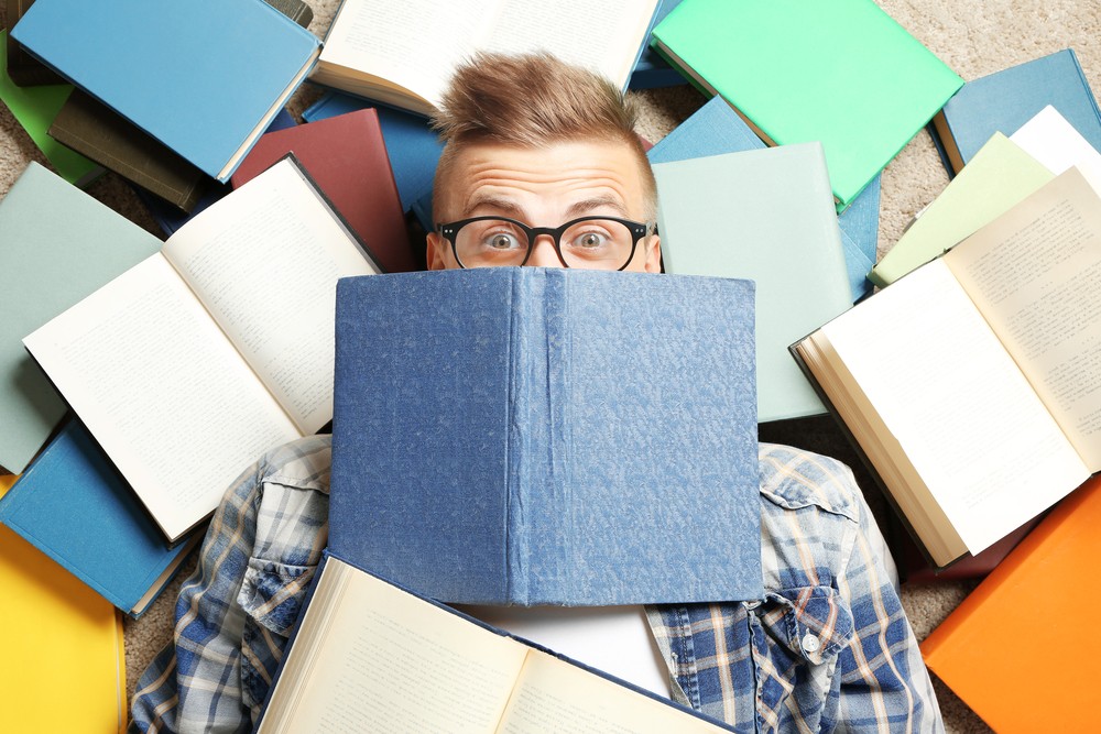 A man is surrounded by books showing that he is doing research.