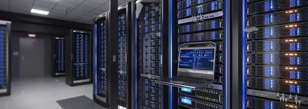 A modern server room with multiple server racks and a pull-out keyboard and monitor displaying data. The servers are lit with blue indicators, and the room has a polished, reflective floor.